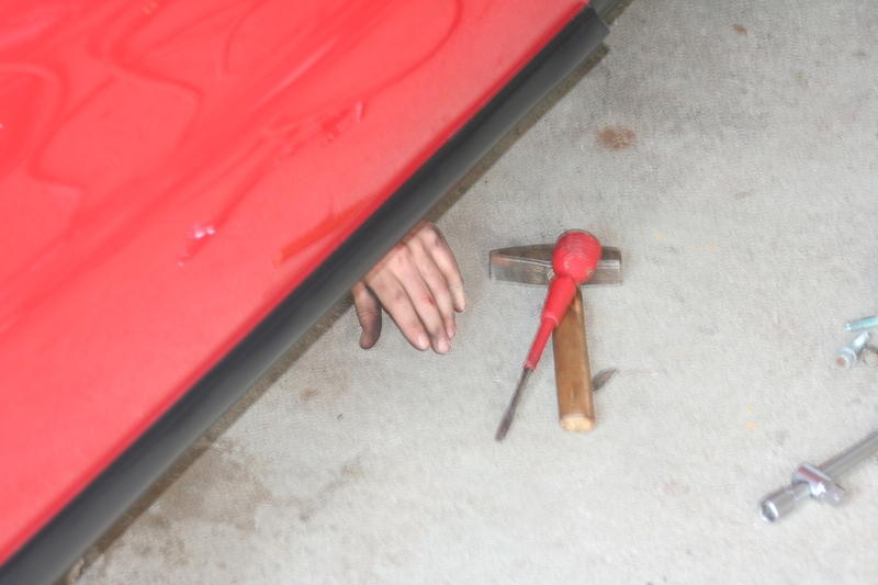 A hand appears under the car